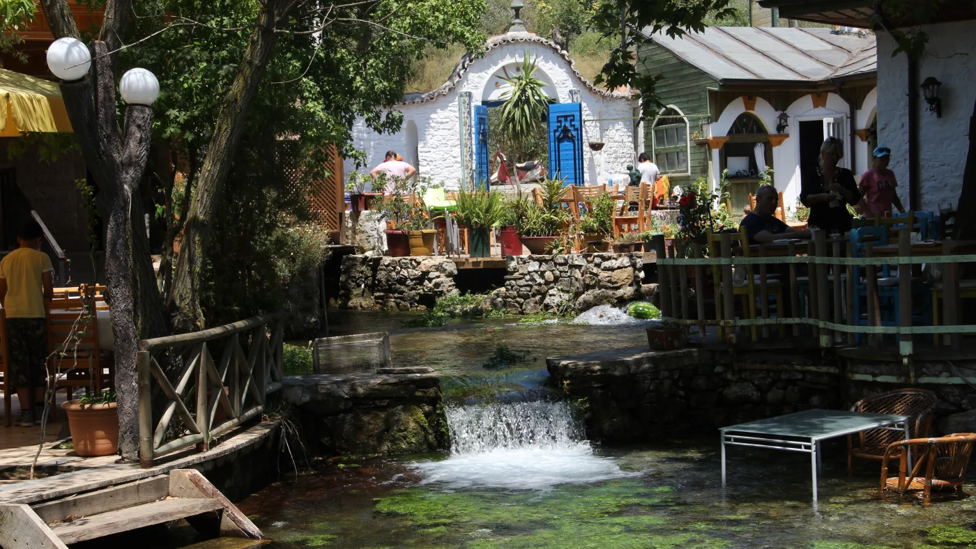 Clear water and traditional buildings beside the Azmak in Akyaka