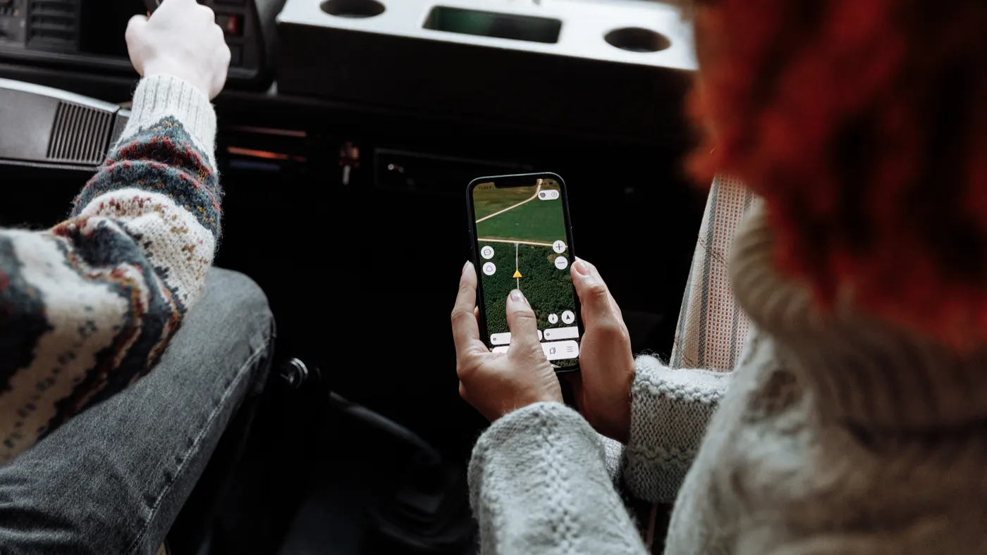 Passenger checking a digital road-trip map inside a car